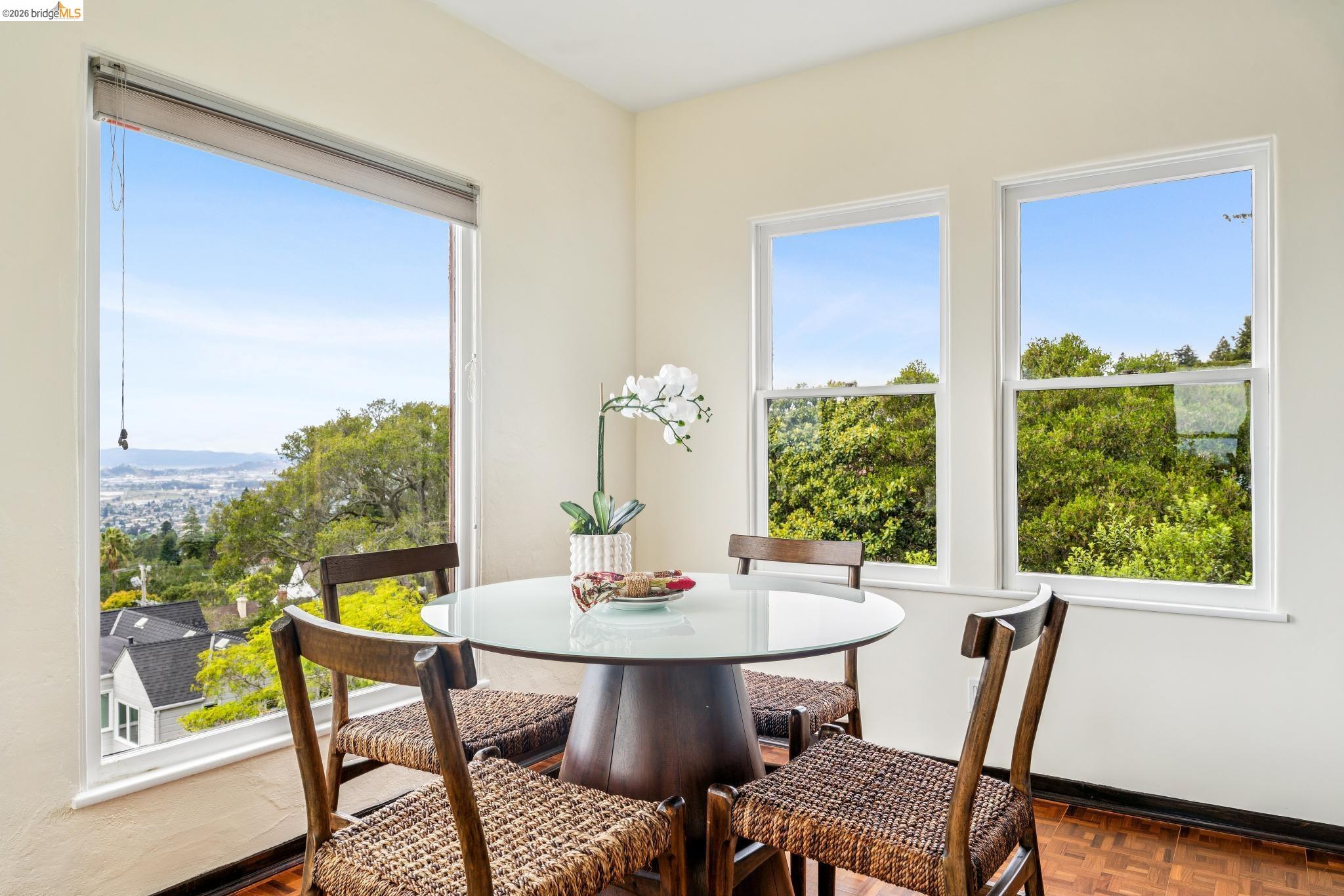 784 Cragmont Avenue Berkeley, CA 94708 - Photo 31 of 64 Corner dining area with a round glass-top table, wood-finish flooring, and multiple windows showcasing a scenic landscape