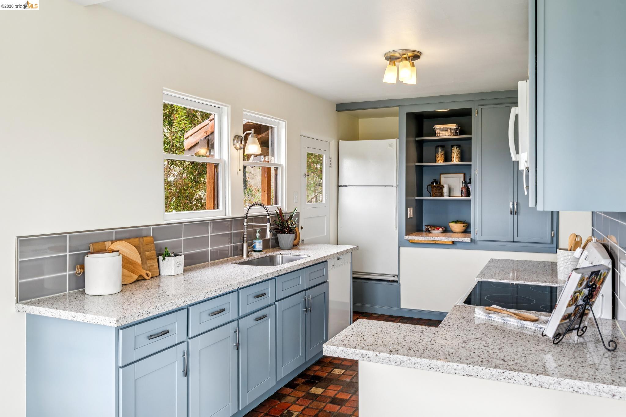 784 Cragmont Avenue Berkeley, CA 94708 - Photo 36 of 64 Kitchen featuring light blue cabinetry, speckled countertops, a subway tile backsplash, recessed shelving, and a built-in cooktop
