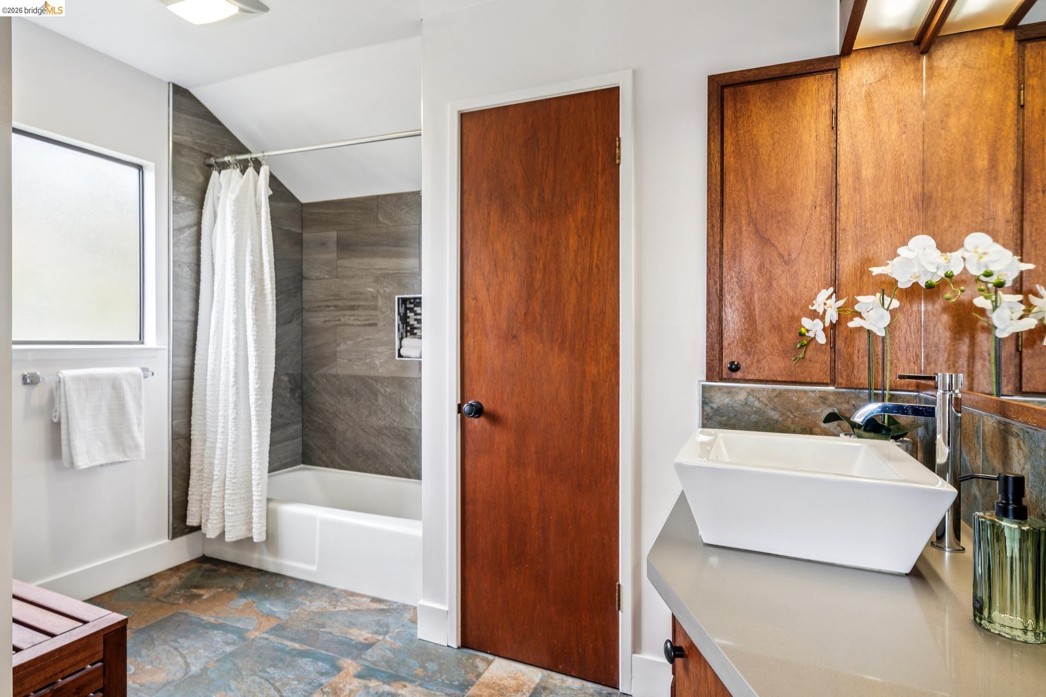 784 Cragmont Avenue Berkeley, CA 94708 - Photo 52 of 64 Bathroom featuring a vessel sink with a contemporary faucet, wood-finish cabinetry, and a bathtub with tile surround