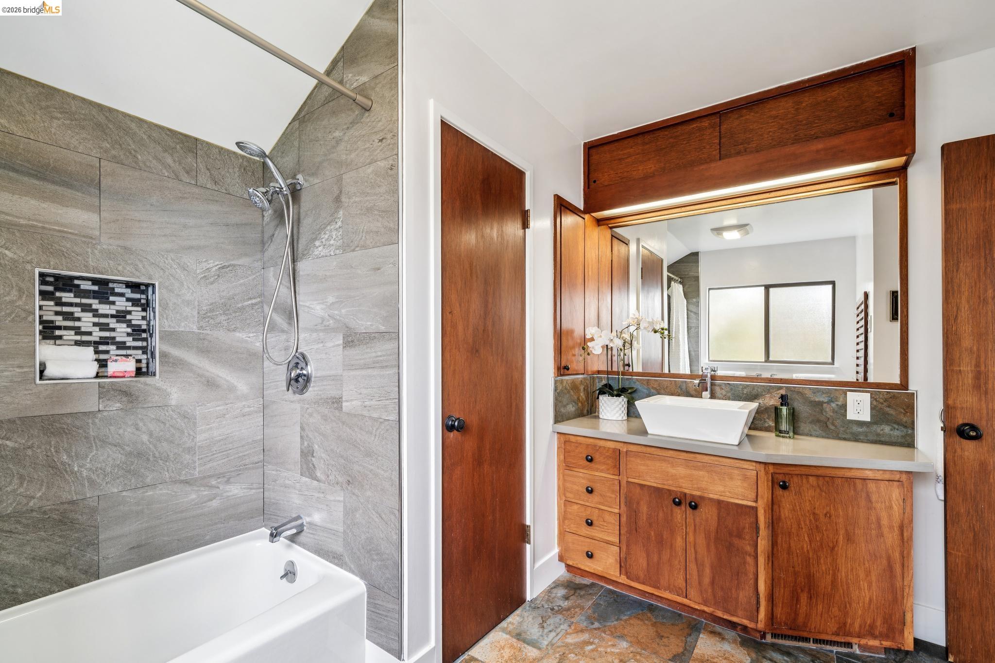 784 Cragmont Avenue Berkeley, CA 94708 - Photo 53 of 64 Bathroom featuring a white tub, chrome shower fixtures, and gray-toned wall tiling with a mosaic-tiled shower niche