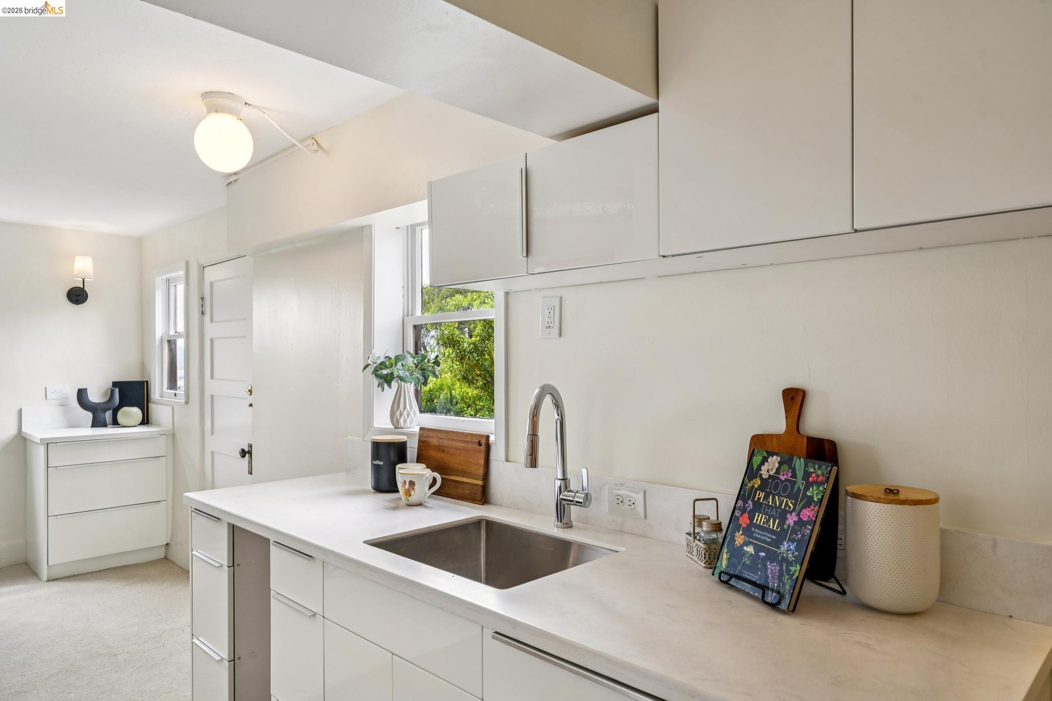784 Cragmont Avenue Berkeley, CA 94708 - Photo 60 of 64 Modern kitchen featuring white cabinetry, light-toned countertops, an undermount stainless steel sink, and a gooseneck faucet