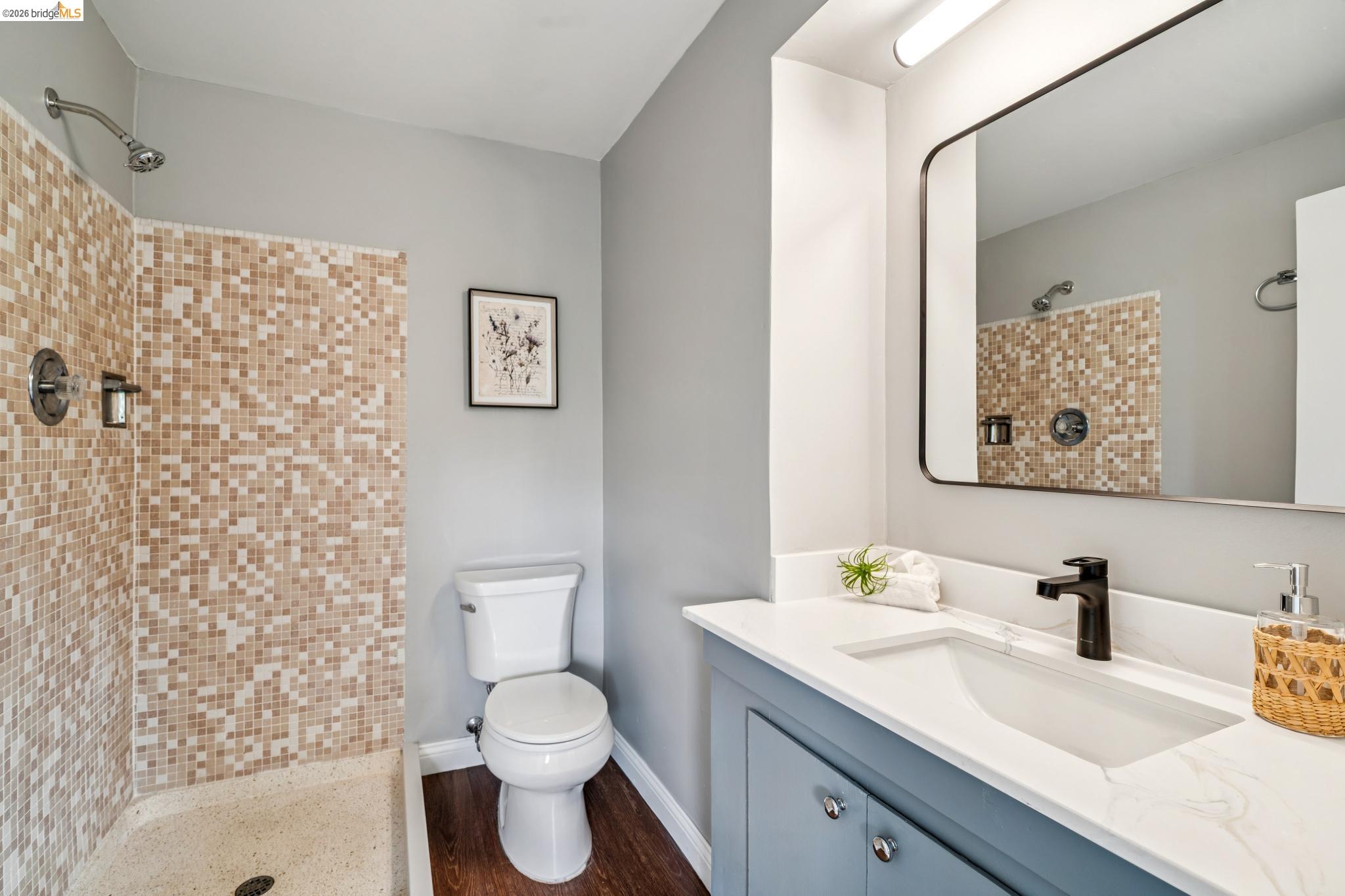 784 Cragmont Avenue Berkeley, CA 94708 - Photo 62 of 64 Contemporary bathroom featuring a mosaic-tiled shower, white toilet, dark wood-finish flooring, and a vanity with a white countertop and rectangular sink