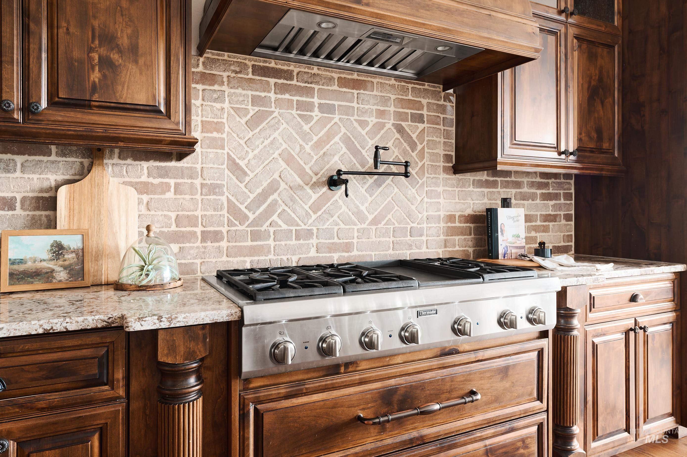3931 North Triple Ridge Place Eagle, ID 83616 - Photo 10 of 45 Kitchen featuring custom exhaust hood, tasteful backsplash, stainless steel gas cooktop, and light stone countertops