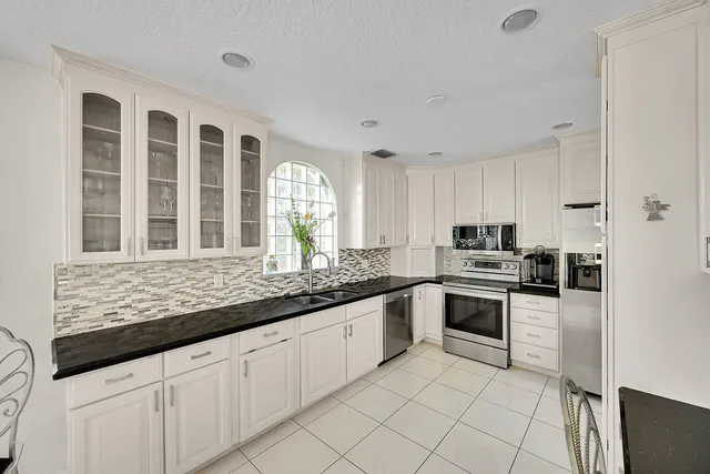 a kitchen with granite countertop white cabinets white appliances and a sink