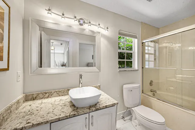 a bathroom with a sink vanity mirror and toilet