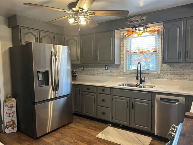 a kitchen with stainless steel appliances granite countertop a refrigerator a sink and a stove