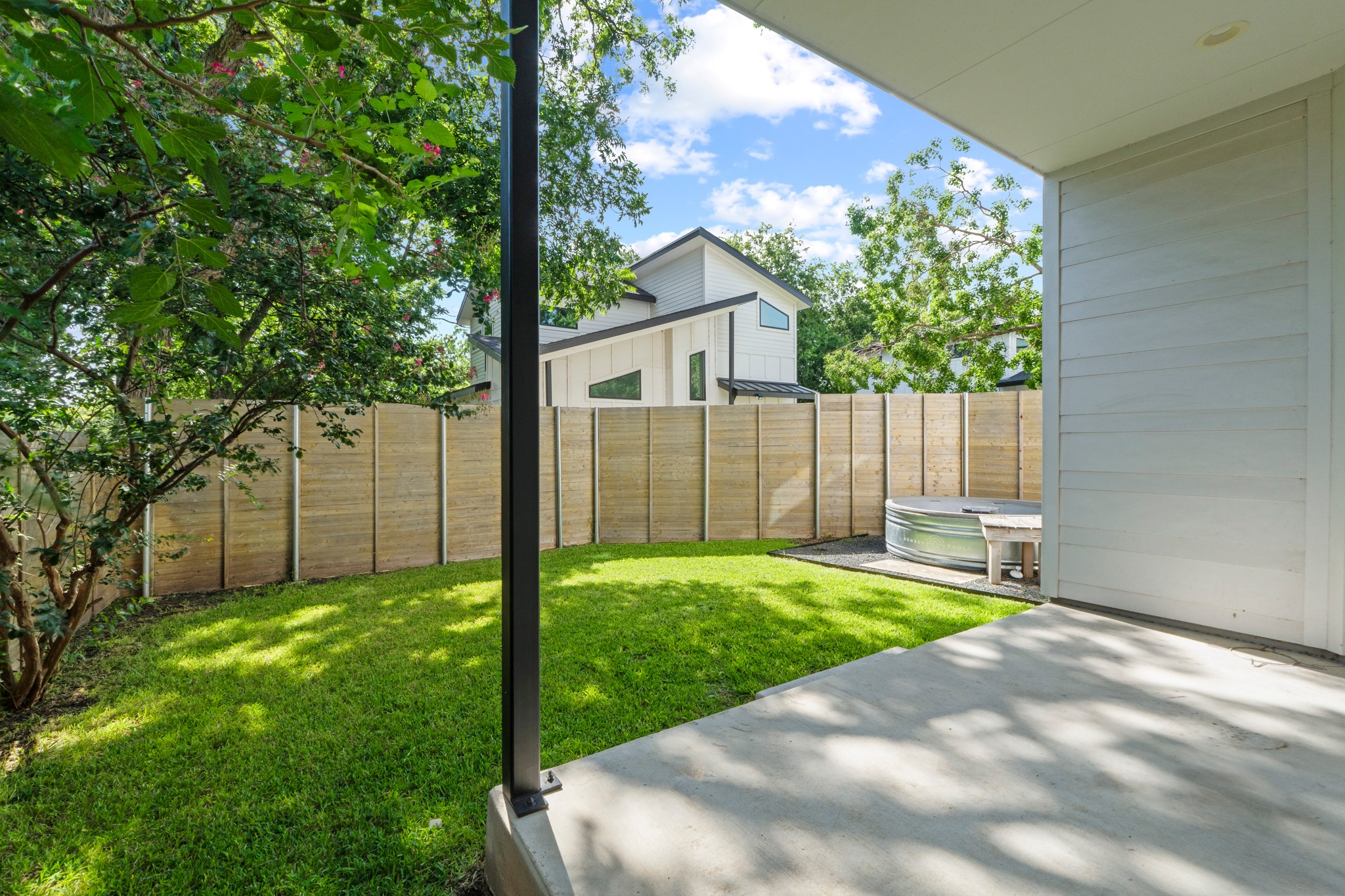 2007 Chestnut Avenue, Unit 1 Austin, TX 78722 - Photo 30 of 32 A spacious, enclosed backyard offers a verdant lawn and a private stock tank for relaxation.