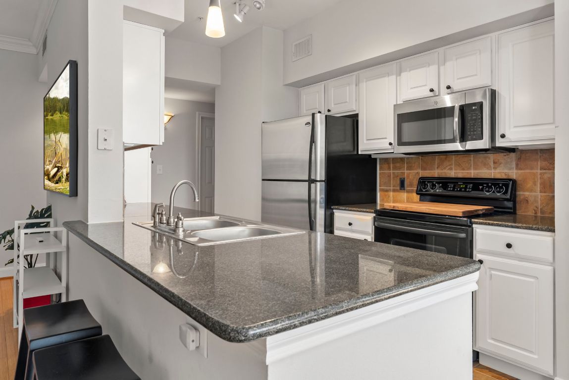 7701 Rialto Boulevard, Unit 1426 Austin, TX 78735 - Photo 4 of 29 a kitchen with stainless steel appliances granite countertop a sink a stove and microwave
