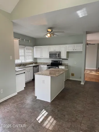 a kitchen with stainless steel appliances a sink a stove a microwave a center island and cabinets