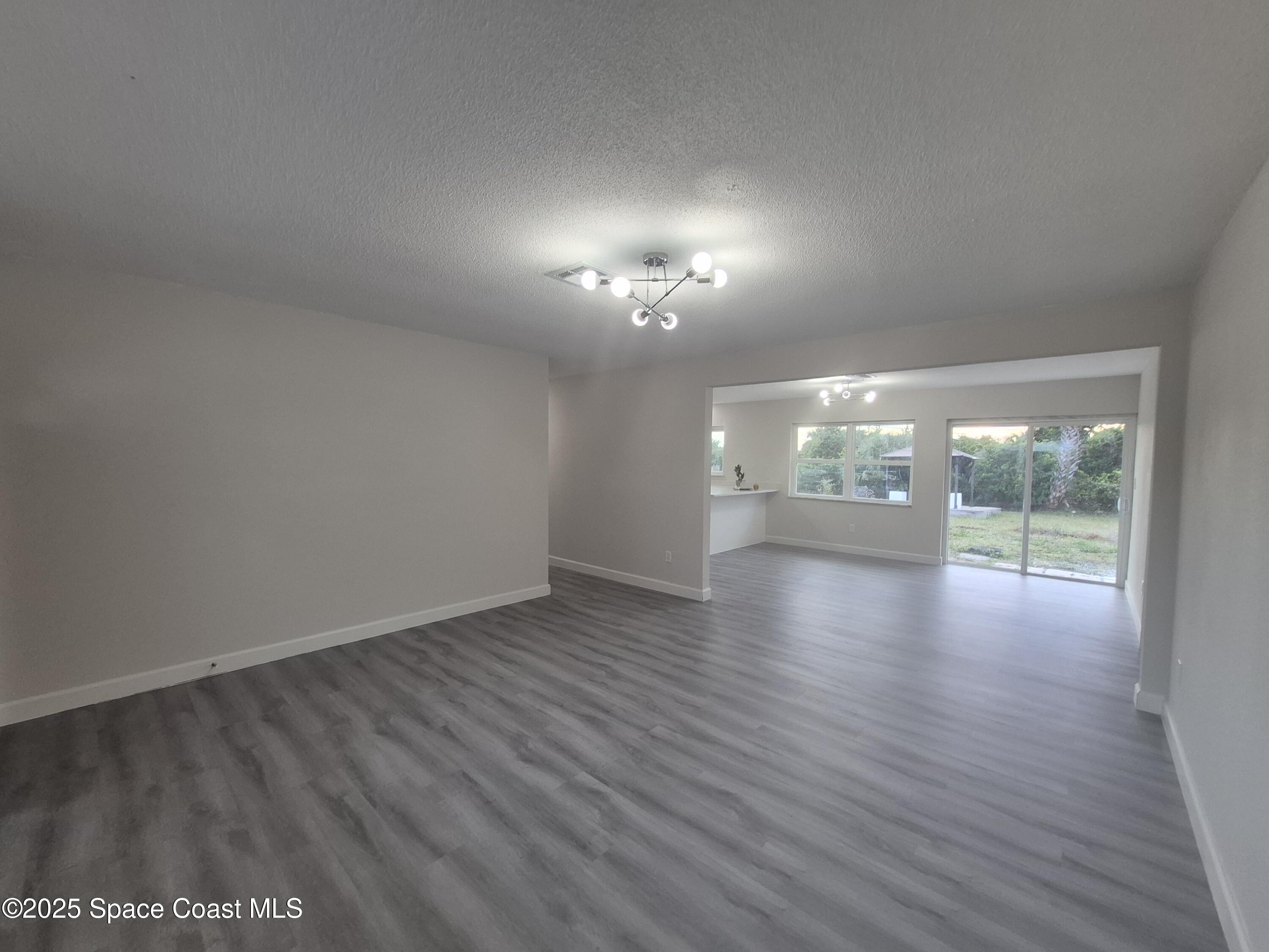 980 Bacon Circle Northeast Palm Bay, FL 32905 - Photo 11 of 50 an empty room with wooden floor and windows