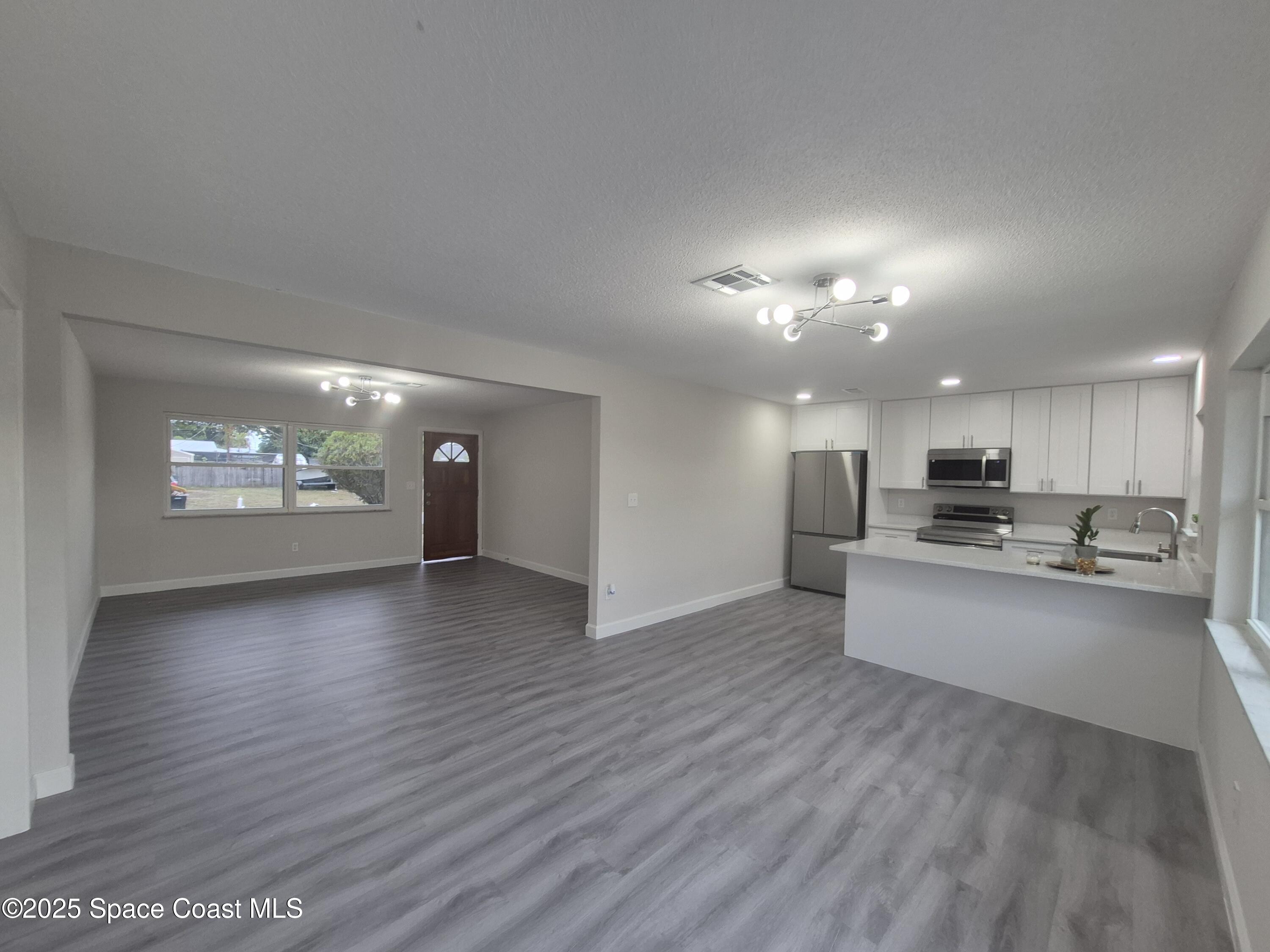 980 Bacon Circle Northeast Palm Bay, FL 32905 - Photo 13 of 50 a view of a living room a kitchen with furniture and a wooden floor