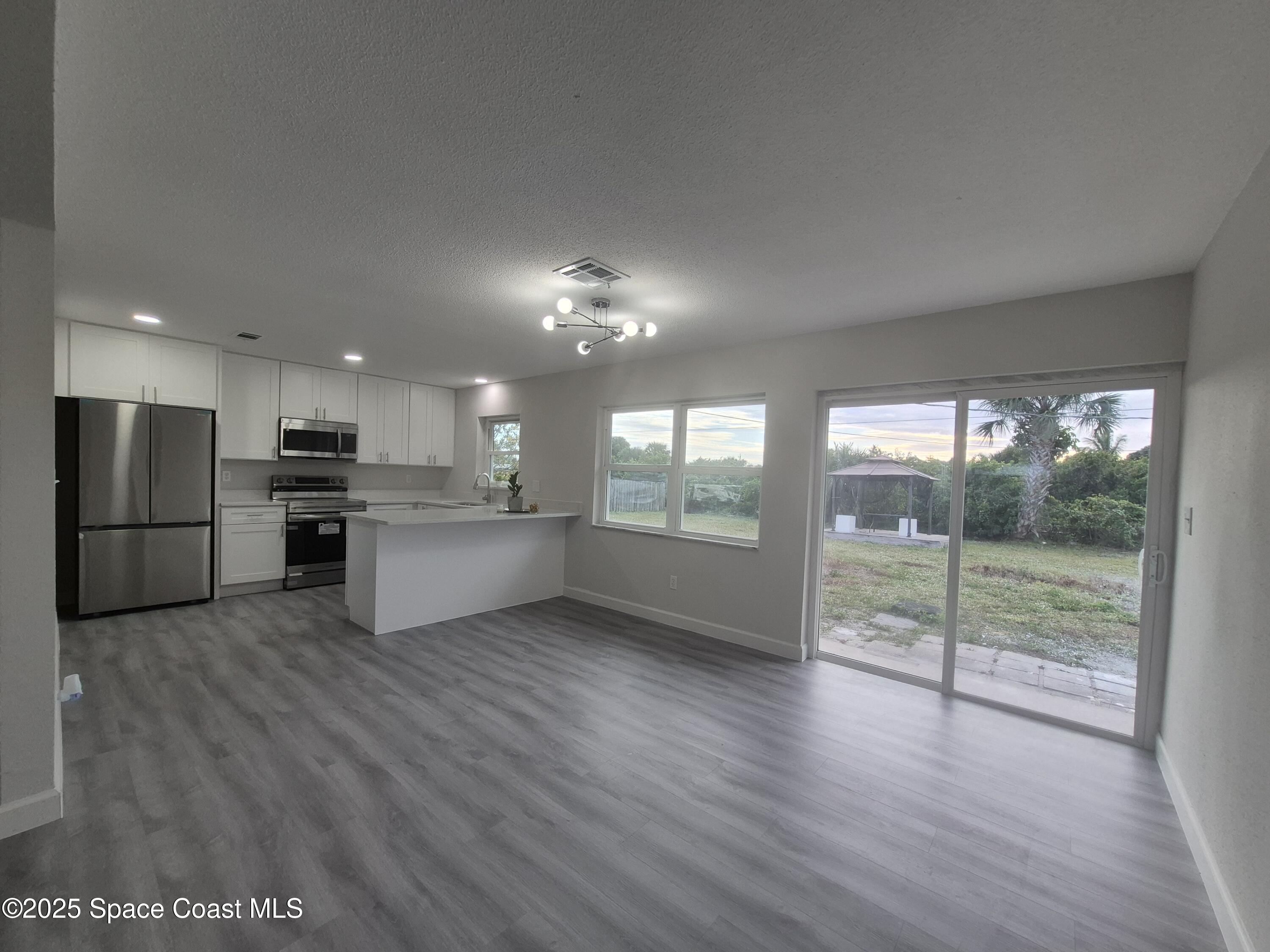 980 Bacon Circle Northeast Palm Bay, FL 32905 - Photo 14 of 50 a view of kitchen with refrigerator and wooden floor