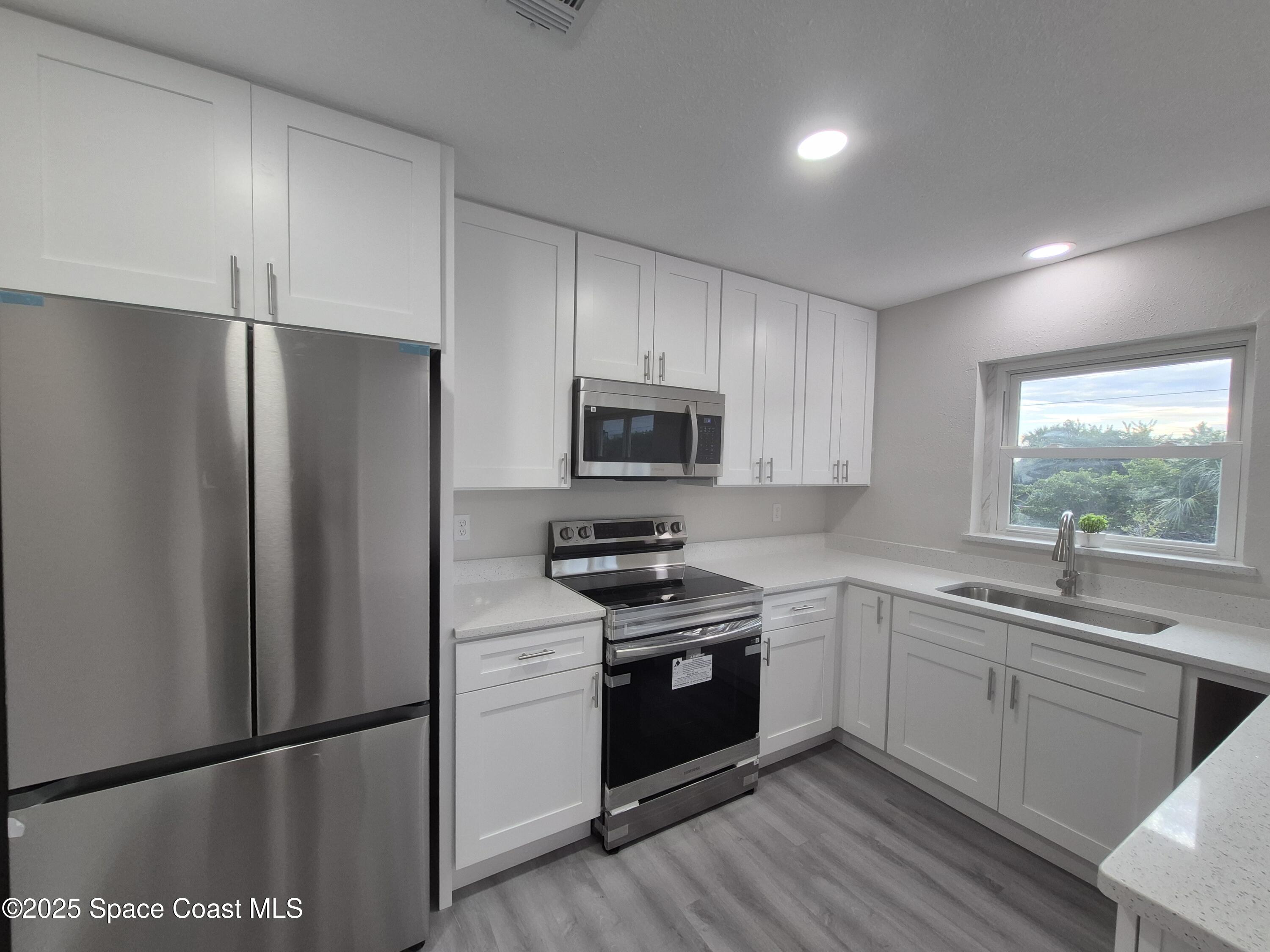 980 Bacon Circle Northeast Palm Bay, FL 32905 - Photo 17 of 50 a kitchen with white cabinets stainless steel appliances and a window