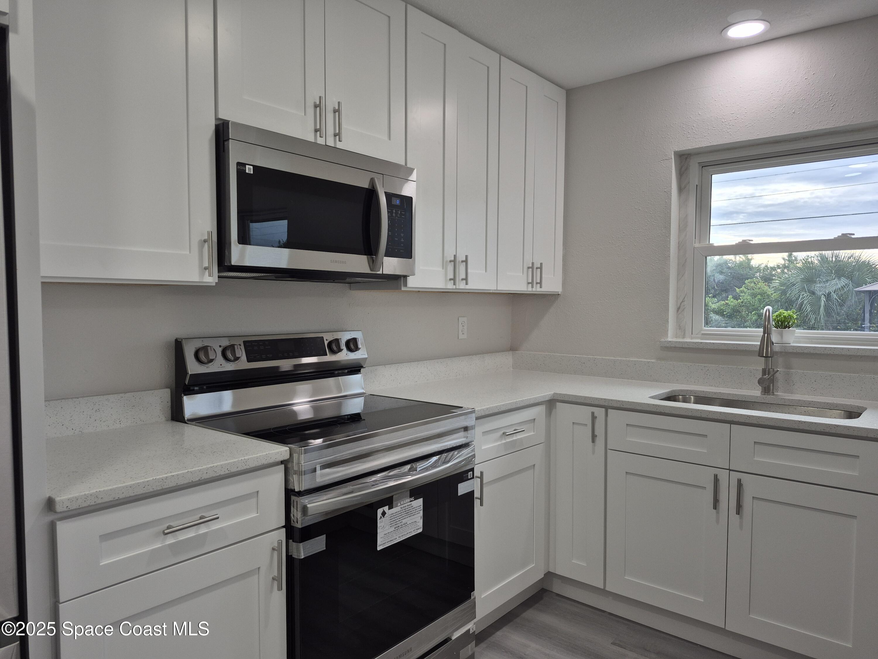 980 Bacon Circle Northeast Palm Bay, FL 32905 - Photo 18 of 50 a kitchen with white cabinets and a stove top oven