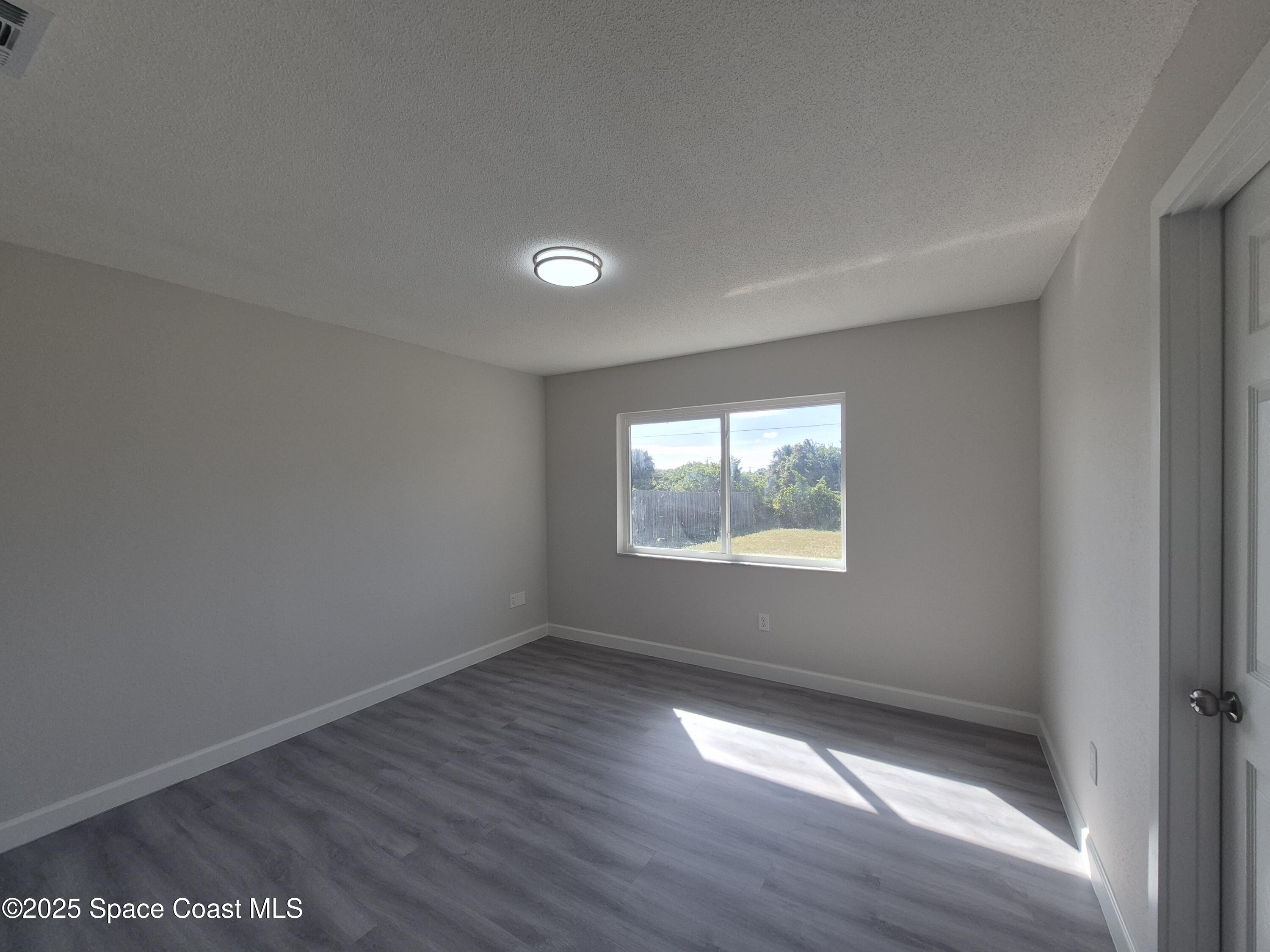 980 Bacon Circle Northeast Palm Bay, FL 32905 - Photo 22 of 50 an empty room with wooden floor and windows
