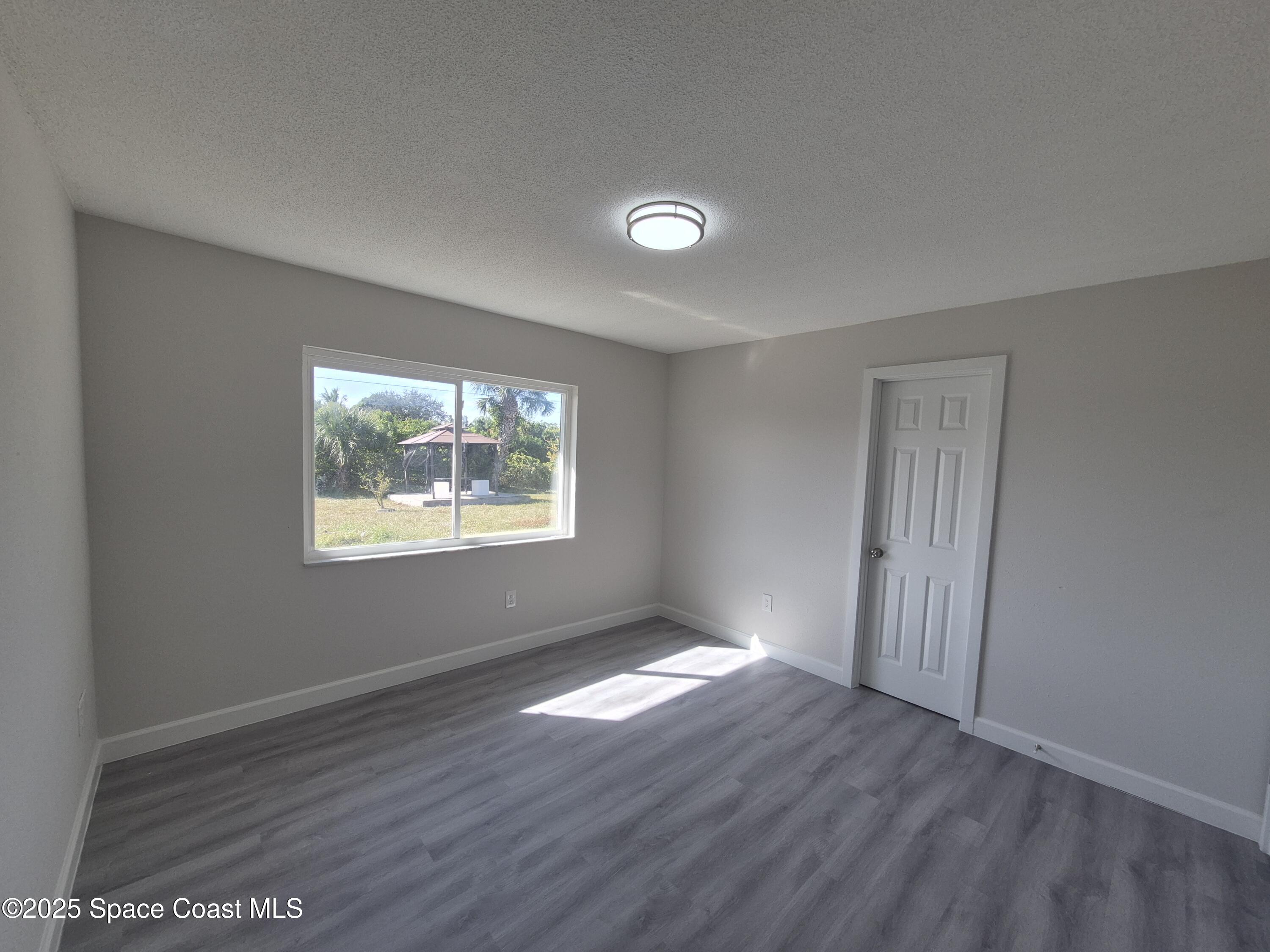 980 Bacon Circle Northeast Palm Bay, FL 32905 - Photo 24 of 50 a view of an empty room with wooden floor and a window
