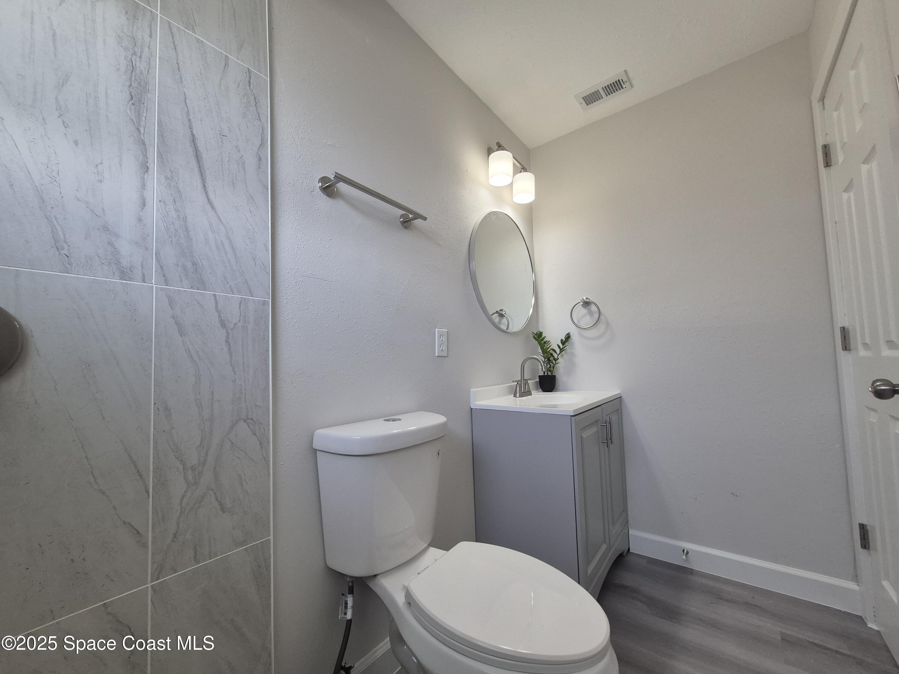 980 Bacon Circle Northeast Palm Bay, FL 32905 - Photo 27 of 50 a white toilet sitting next to a bathroom sink and vanity