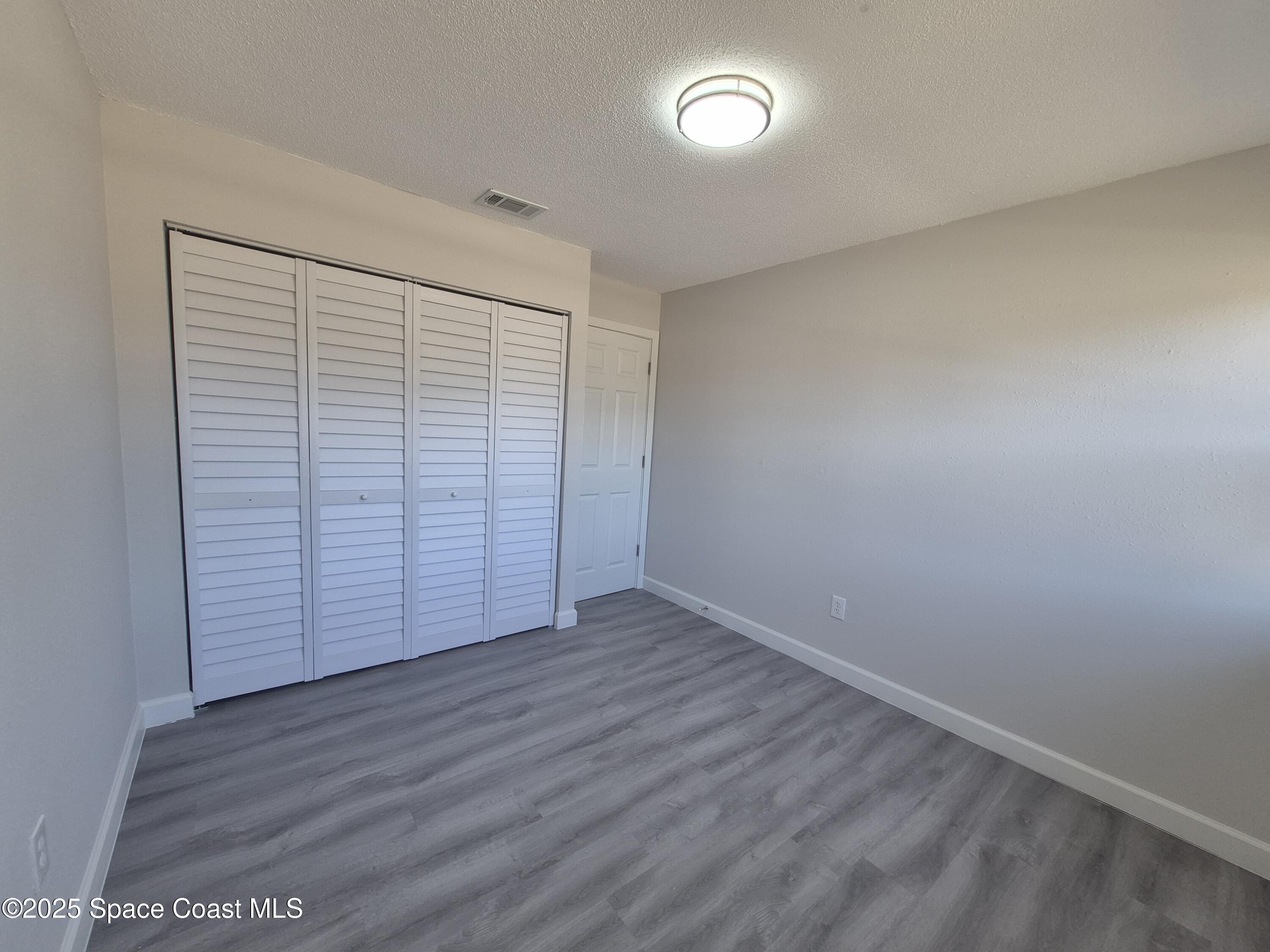 980 Bacon Circle Northeast Palm Bay, FL 32905 - Photo 29 of 50 an empty room with wooden floor and windows