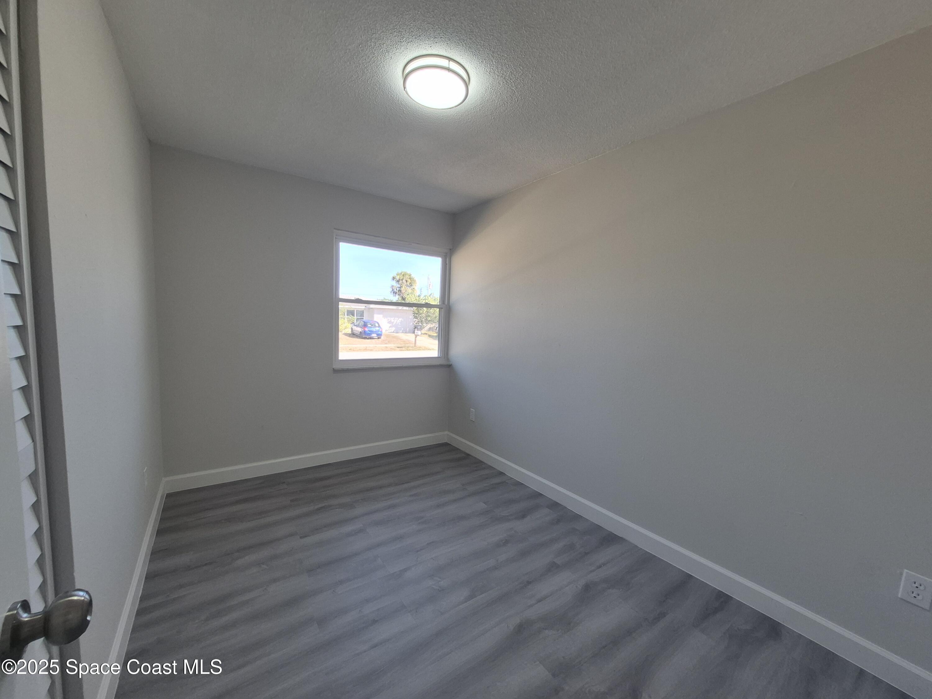 980 Bacon Circle Northeast Palm Bay, FL 32905 - Photo 30 of 50 an empty room with wooden floor and windows