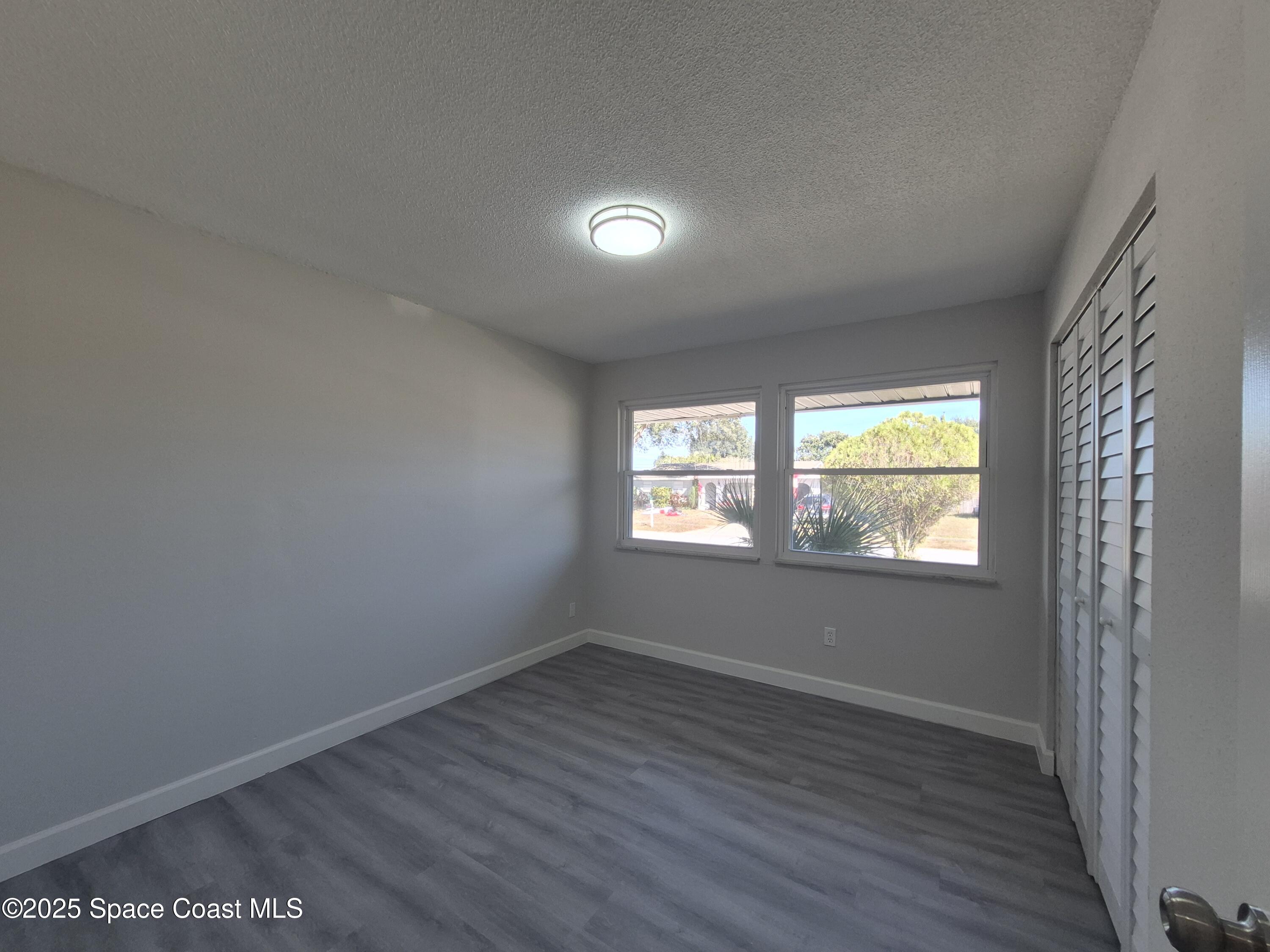 980 Bacon Circle Northeast Palm Bay, FL 32905 - Photo 32 of 50 an empty room with wooden floor and windows