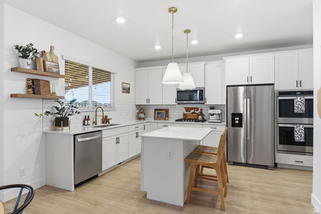 596 South Meade Street Mapleton, UT 84664 - Photo 7 of 38 Kitchen with stainless steel appliances, white cabinetry, a kitchen island, and a breakfast bar