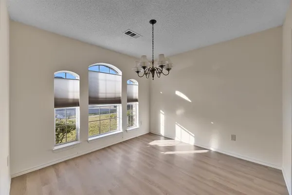 a view of a room with wooden floor chandelier and windows