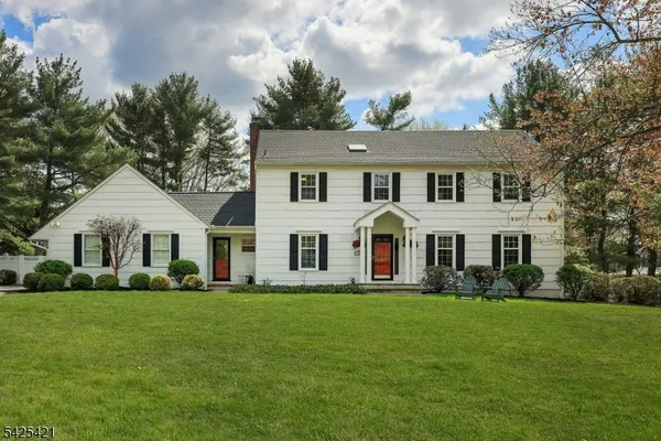 a front view of a house with a garden and trees