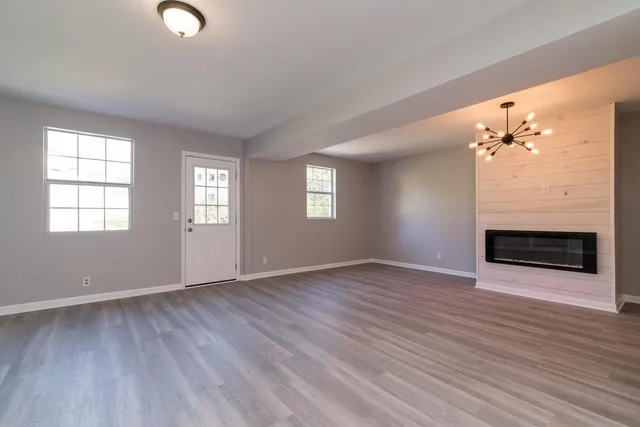 an empty room with wooden floor fireplace and windows