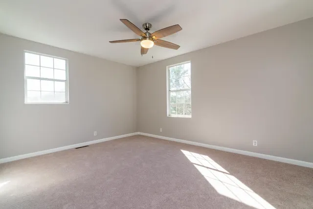 an empty room with window and ceiling fan