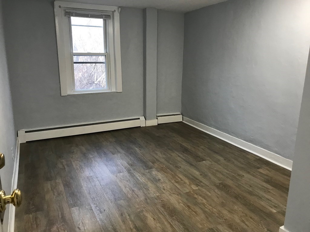 176 Plymouth Street, Unit 2 Bridgewater, MA 02324 - Photo 9 of 11 an empty room with wooden floor and windows