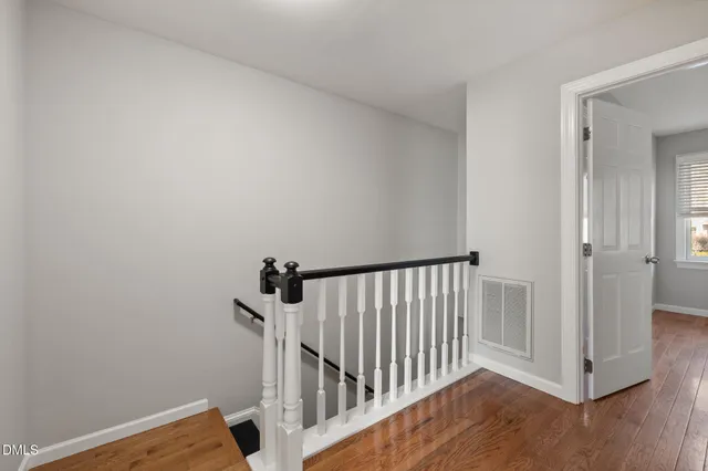 a view of a hallway with wooden floor and a bathroom