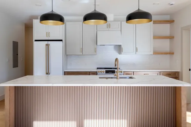 a kitchen with stainless steel appliances a refrigerator a stove a chimney a sink and a counter