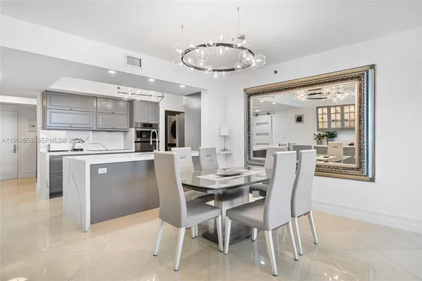 a dining room with stainless steel appliances kitchen island granite countertop a table chairs and a refrigerator