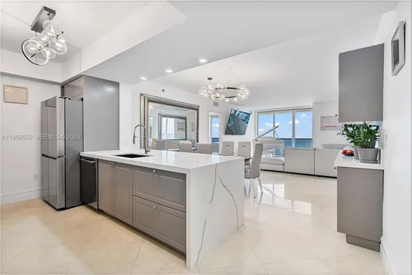 a kitchen with stainless steel appliances granite countertop a refrigerator a sink dishwasher a stove and white cabinets with wooden floor
