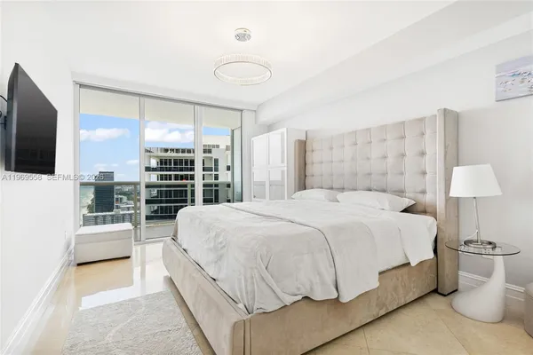 a spacious bedroom with a bed and a flat screen tv