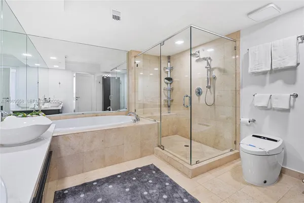 a bathroom with a bathtub shower sink mirror and toilet