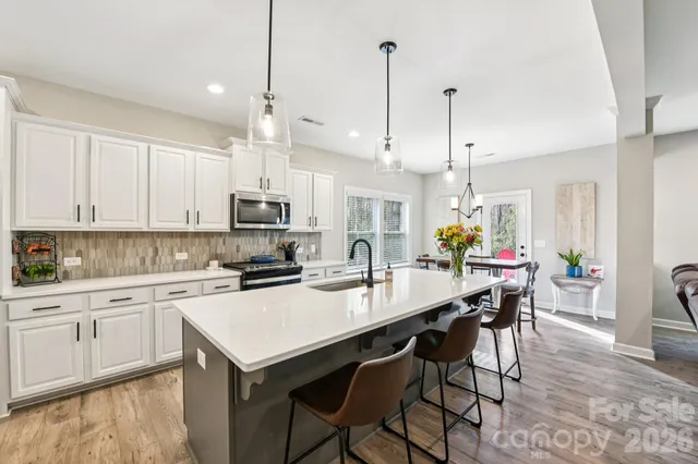 a kitchen with stainless steel appliances kitchen island a table chairs and a refrigerator