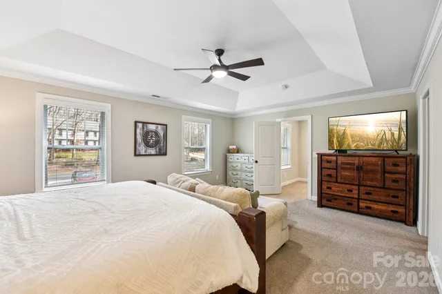 a spacious bedroom with a bed a dresser and a chandelier