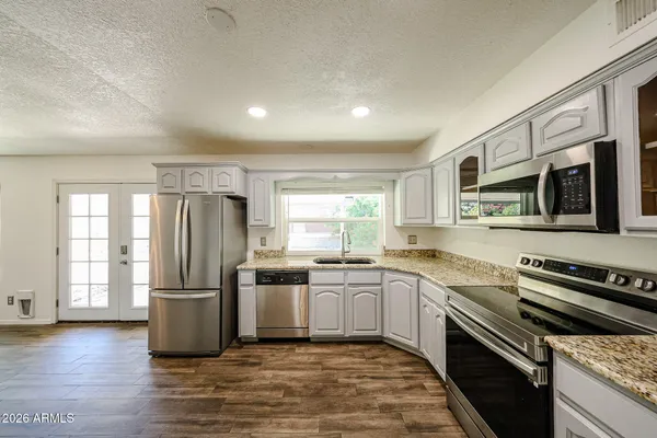 a kitchen with stainless steel appliances granite countertop a refrigerator stove microwave and sink