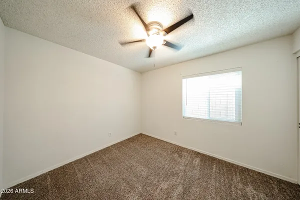 an empty room with a window and a fan