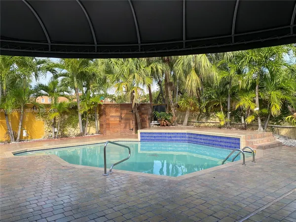 a view of a swimming pool with lawn chairs under an umbrella
