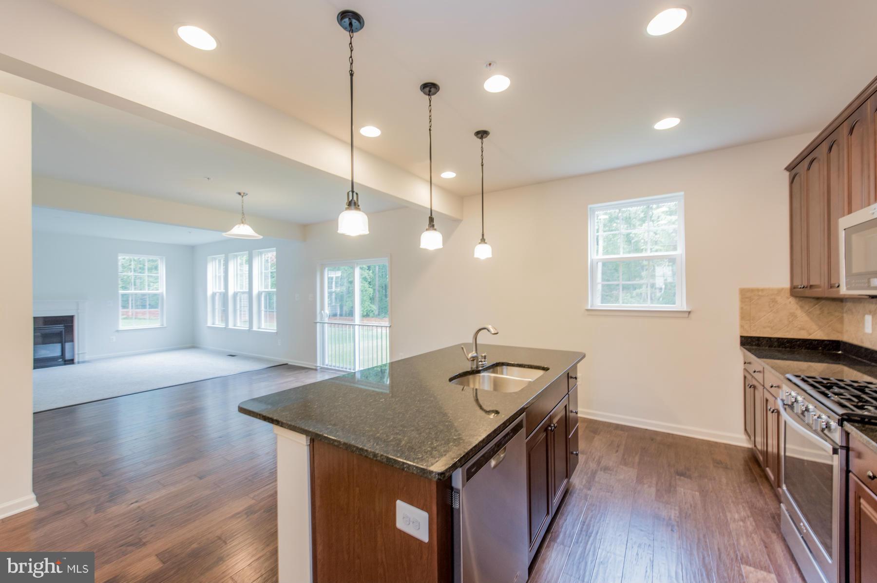 10515 Braddock Run Road Middle River, MD 21220 - Photo 6 of 27 a kitchen with granite countertop a stove a sink dishwasher a refrigerator and a dining table with wooden floor