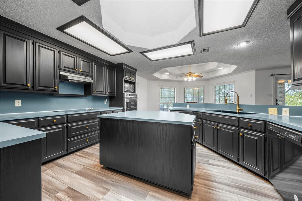 215 Lajuana Drive Waco, TX 76705 - Photo 12 of 33 Kitchen with a tray ceiling, a textured ceiling, a center island, black appliances, and ceiling fan
