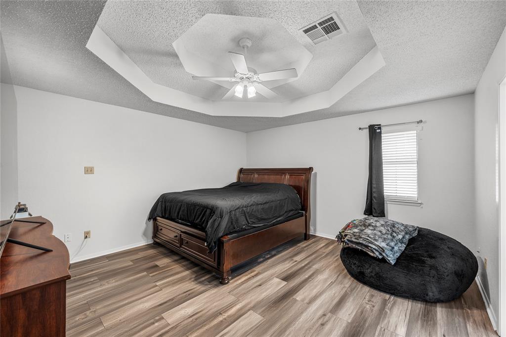 215 Lajuana Drive Waco, TX 76705 - Photo 16 of 33 Bedroom with a tray ceiling, a textured ceiling, wood finished floors, and ceiling fan