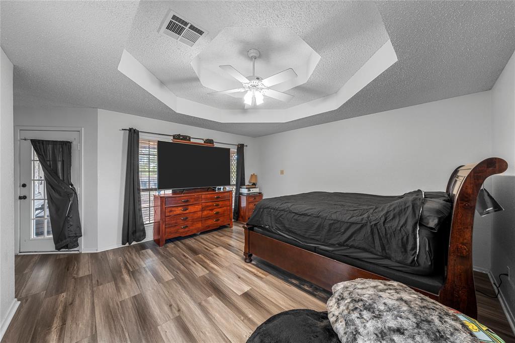 215 Lajuana Drive Waco, TX 76705 - Photo 17 of 33 Bedroom featuring a raised ceiling, a textured ceiling, wood finished floors, and ceiling fan