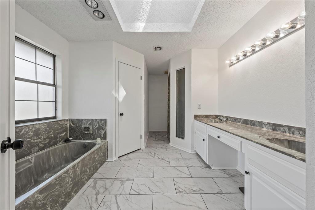 215 Lajuana Drive Waco, TX 76705 - Photo 18 of 33 Bathroom featuring a textured ceiling, a bath, double vanity, and light marble finish floors
