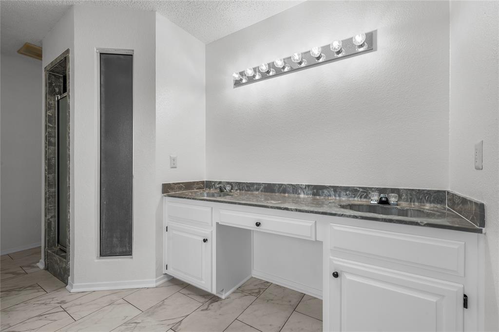 215 Lajuana Drive Waco, TX 76705 - Photo 19 of 33 Full bathroom featuring double vanity, light marble finish floors, a shower stall, and a textured ceiling