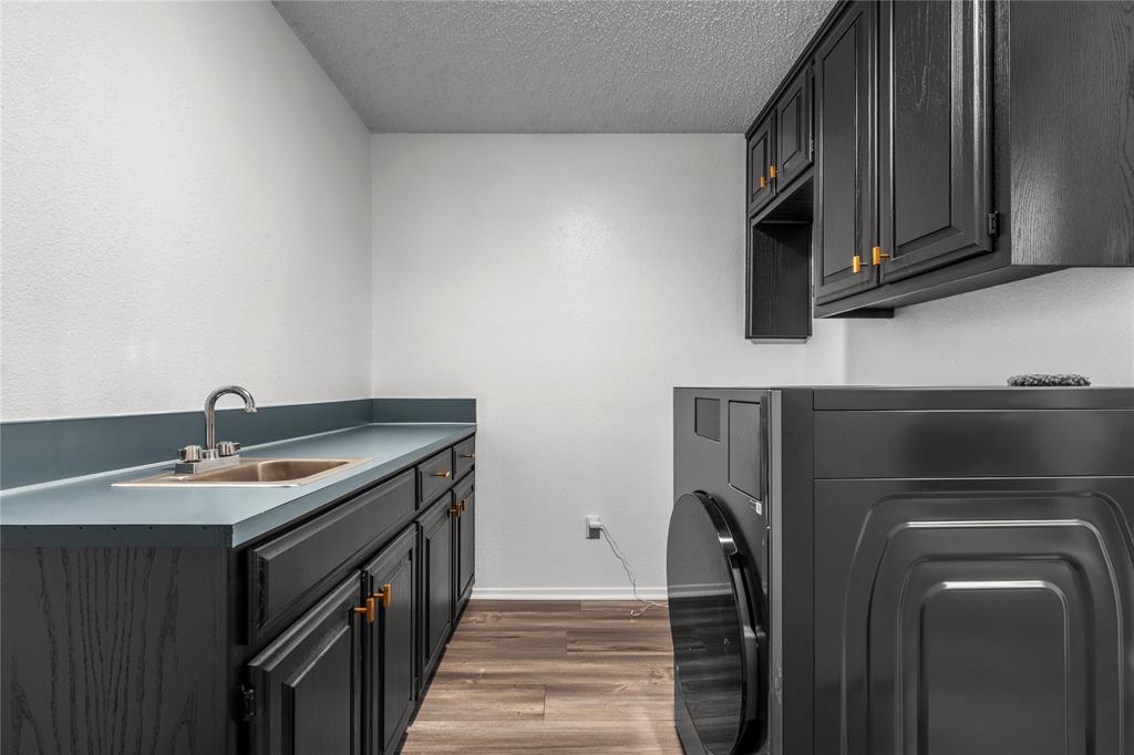 215 Lajuana Drive Waco, TX 76705 - Photo 25 of 33 Laundry area featuring cabinet space, dark wood-type flooring, and a textured ceiling