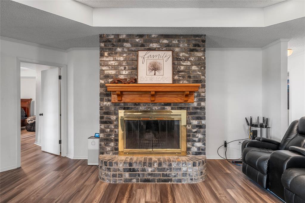 215 Lajuana Drive Waco, TX 76705 - Photo 6 of 33 Living area featuring a textured ceiling, a fireplace, dark wood-type flooring, and ornamental molding
