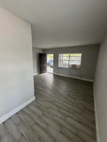 a view of an empty room with window and wooden floor